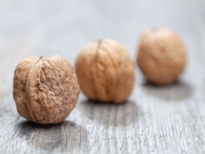 Drei Walnüsse liegen auf einem Holztisch