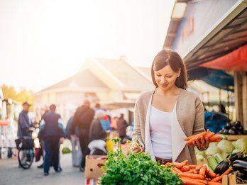Young woman on the market buying vegetables.