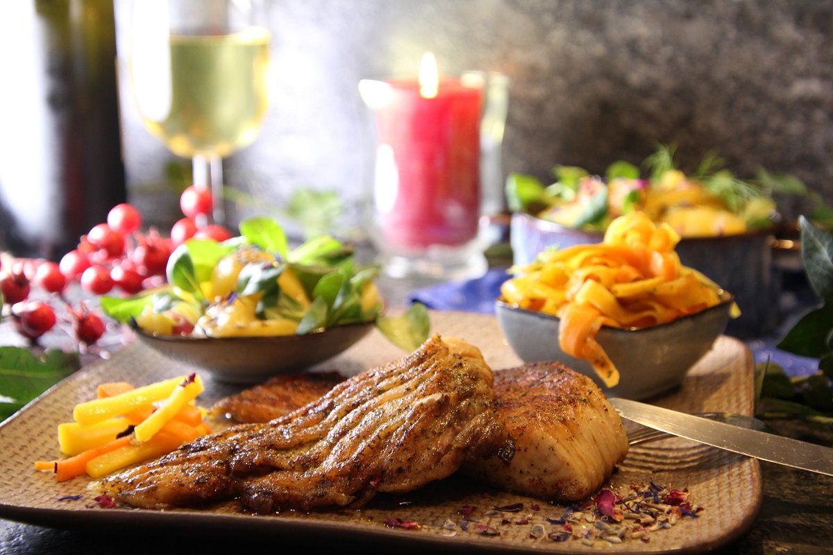 Karpfen angerichtet mit Salat, Nudeln, Wein, Kerze auf Holzbrett ©Elisabeth Heidegger/LK Niederösterreich