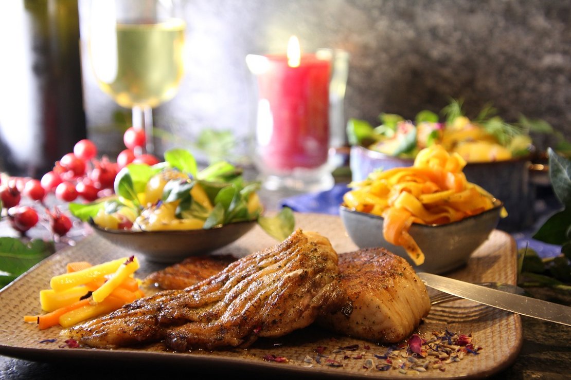 Karpfen angerichtet mit Salat, Nudeln, Wein, Kerze auf Holzbrett ©Elisabeth Heidegger/LK Niederösterreich