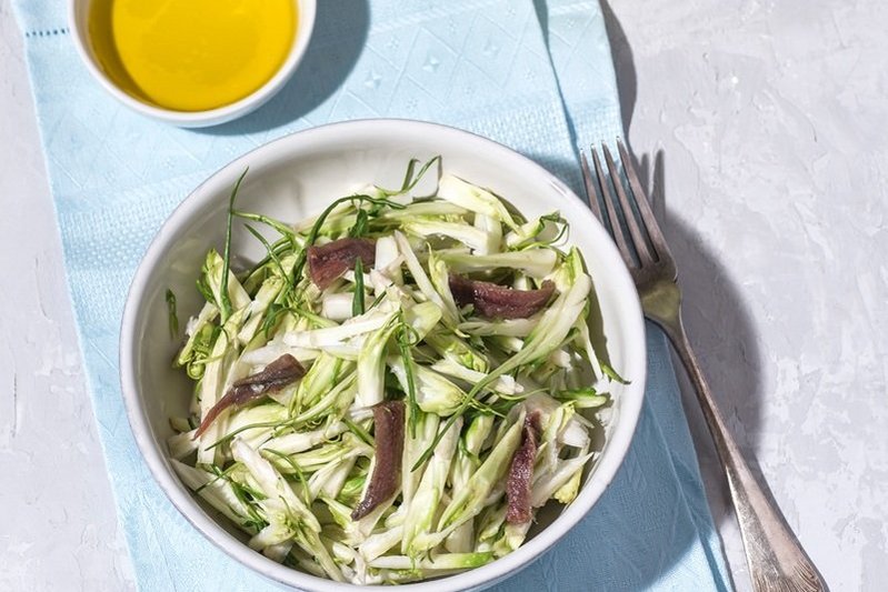 Puntarelle alla romana or asparagus Catalonian chicory salad with anchovy dressing and olive oil, italian food, selective focus, bright sunlight. Italian traditional seasoning recepies