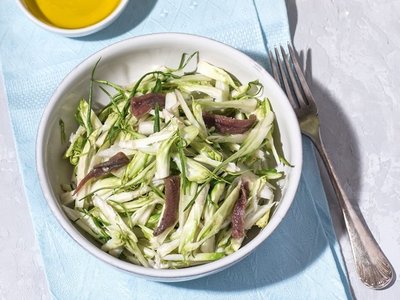 Puntarelle alla romana or asparagus Catalonian chicory salad with anchovy dressing and olive oil, italian food, selective focus, bright sunlight. Italian traditional seasoning recepies
