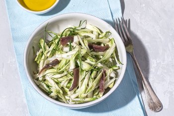 Puntarelle alla romana or asparagus Catalonian chicory salad with anchovy dressing and olive oil, italian food, selective focus, bright sunlight. Italian traditional seasoning recepies