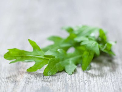 Etwas Rucola liegt auf einem Holztisch