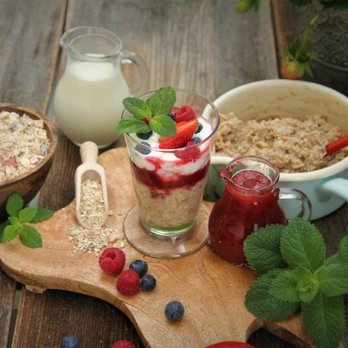 Frühstücksporridge aus Haferflocken und Beeren im Glas samt Zutaten