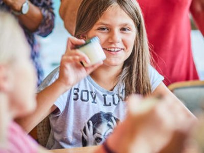 Kind hält Glas mit selbstgemachter Butter in die Höhe