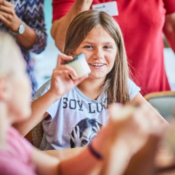 Kind hält Glas mit selbstgemachter Butter in die Höhe