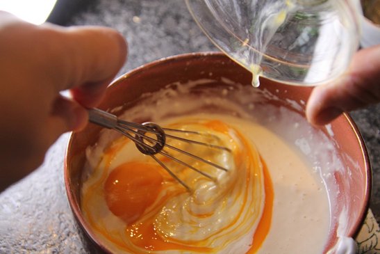 Den Dotter zu dem Mehl-Milch-Gemisch hinzufügen.