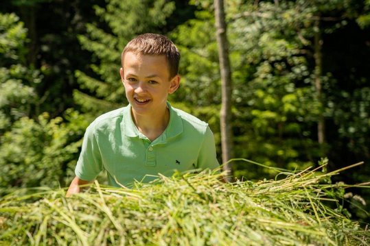 Kind bei der Wiensenmahd führt Wiese in Schiebetruhe