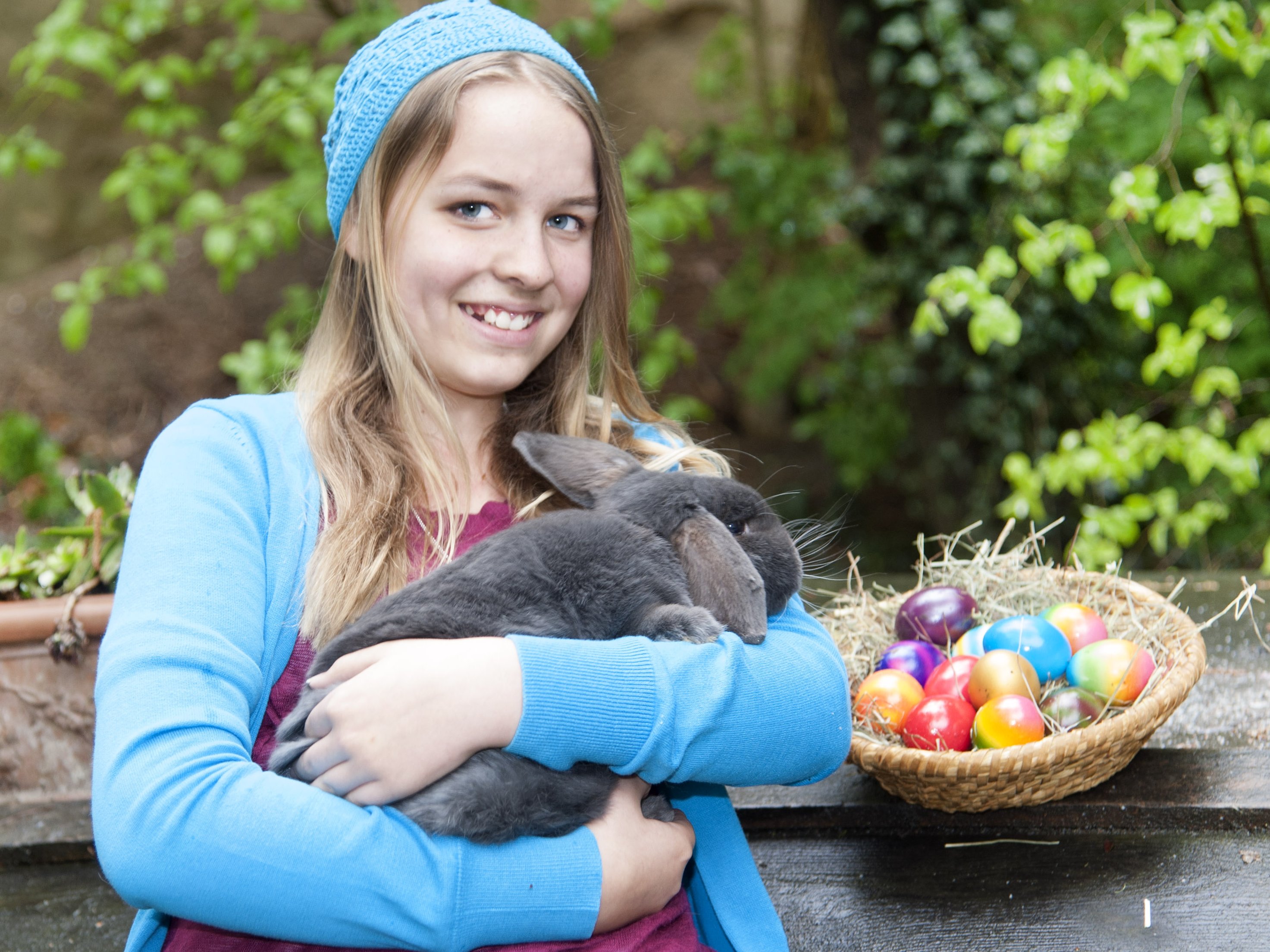 Mädchen mit bunten Ostereieren und Osterhasen auf dem Arm