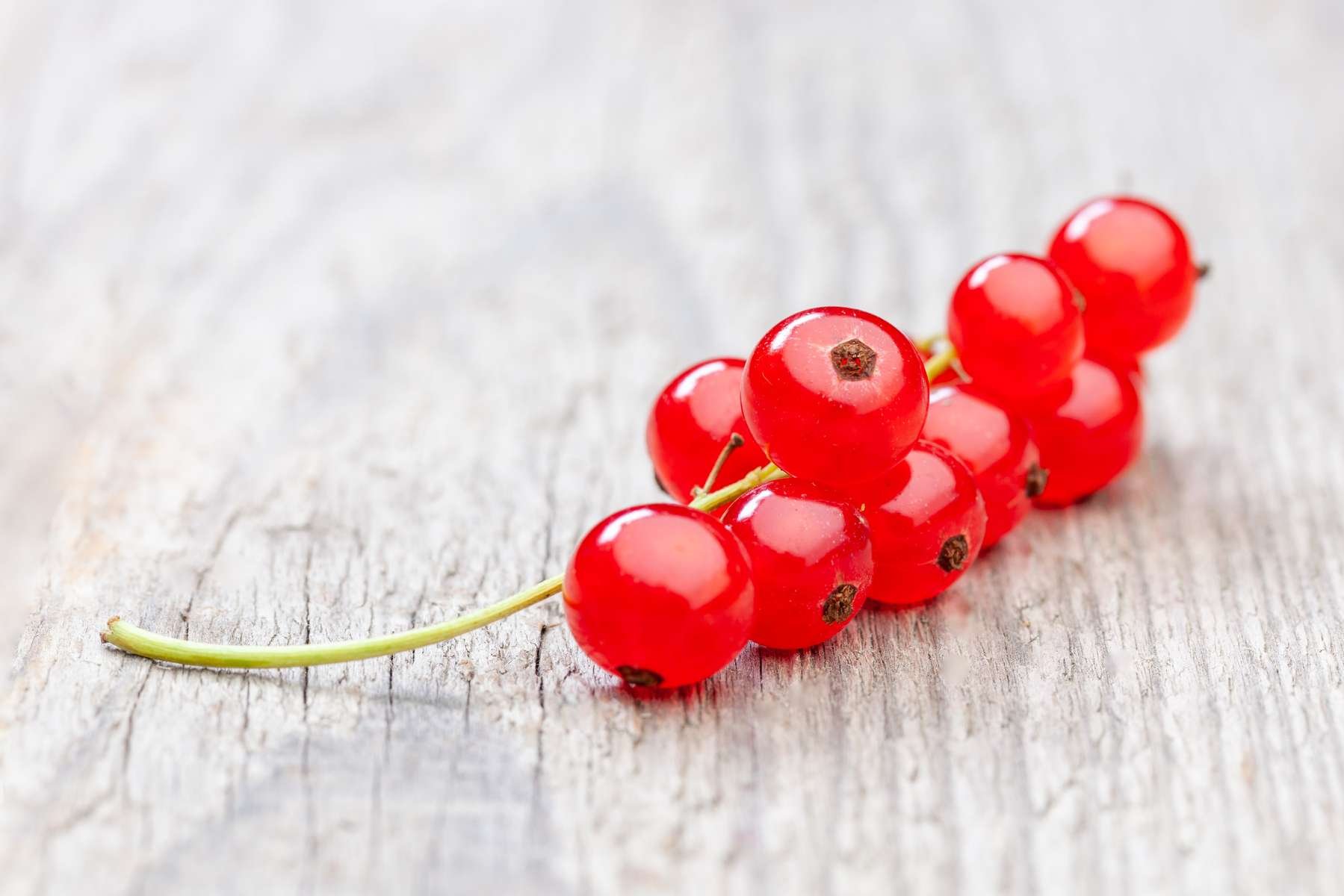 Ein Träubchen Johannisbeeren liegt auf einem Holztisch