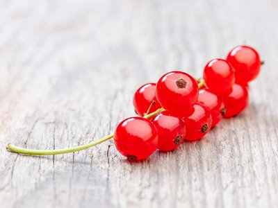 Ein Träubchen Johannisbeeren liegt auf einem Holztisch