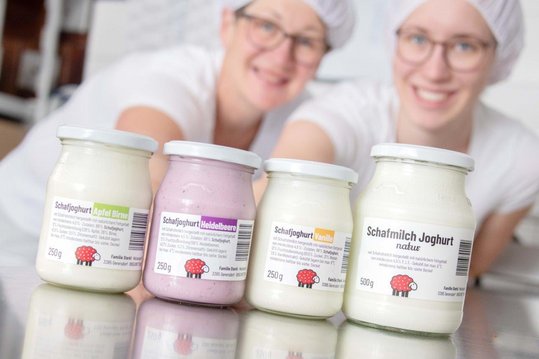 Joghurt aus Schafmilch in verschiedenen Sorten im Hintergrund die beiden Schafbäuerinnen