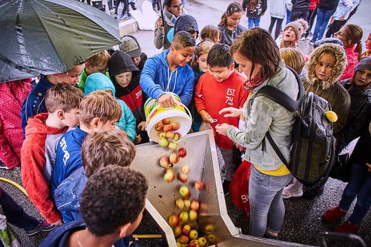 Groß und Klein helfen beim Befüllen der Apfelsaftpresse.
