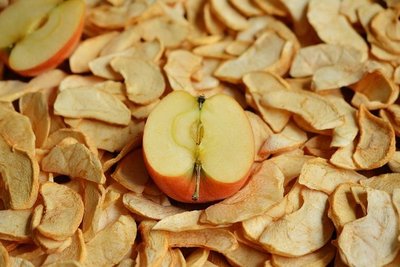 Auf getrockneten Apfelspalten liegt ein halber frischer Apfel