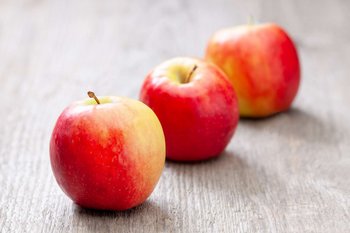 Drei Äpfel liegen auf einem Holztisch