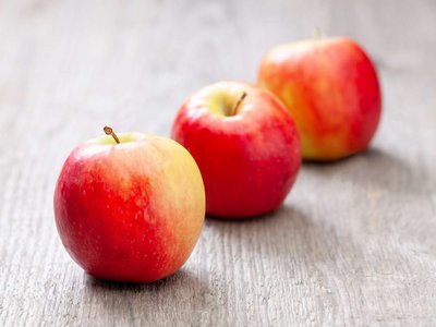 Drei Äpfel liegen auf einem Holztisch