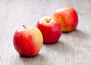 Drei Äpfel liegen auf einem Holztisch