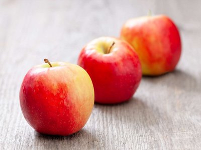 Drei Äpfel liegen auf einem Holztisch