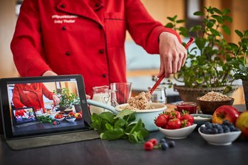Frau kocht vor Kamera und Tablet