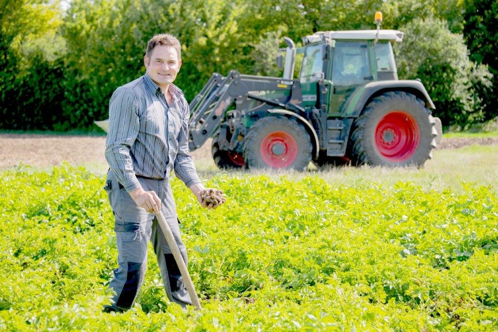 Landwirt Franz Bachl steht auf seinem Erdäpfelacker, im Hintergrund sein Traktor. 