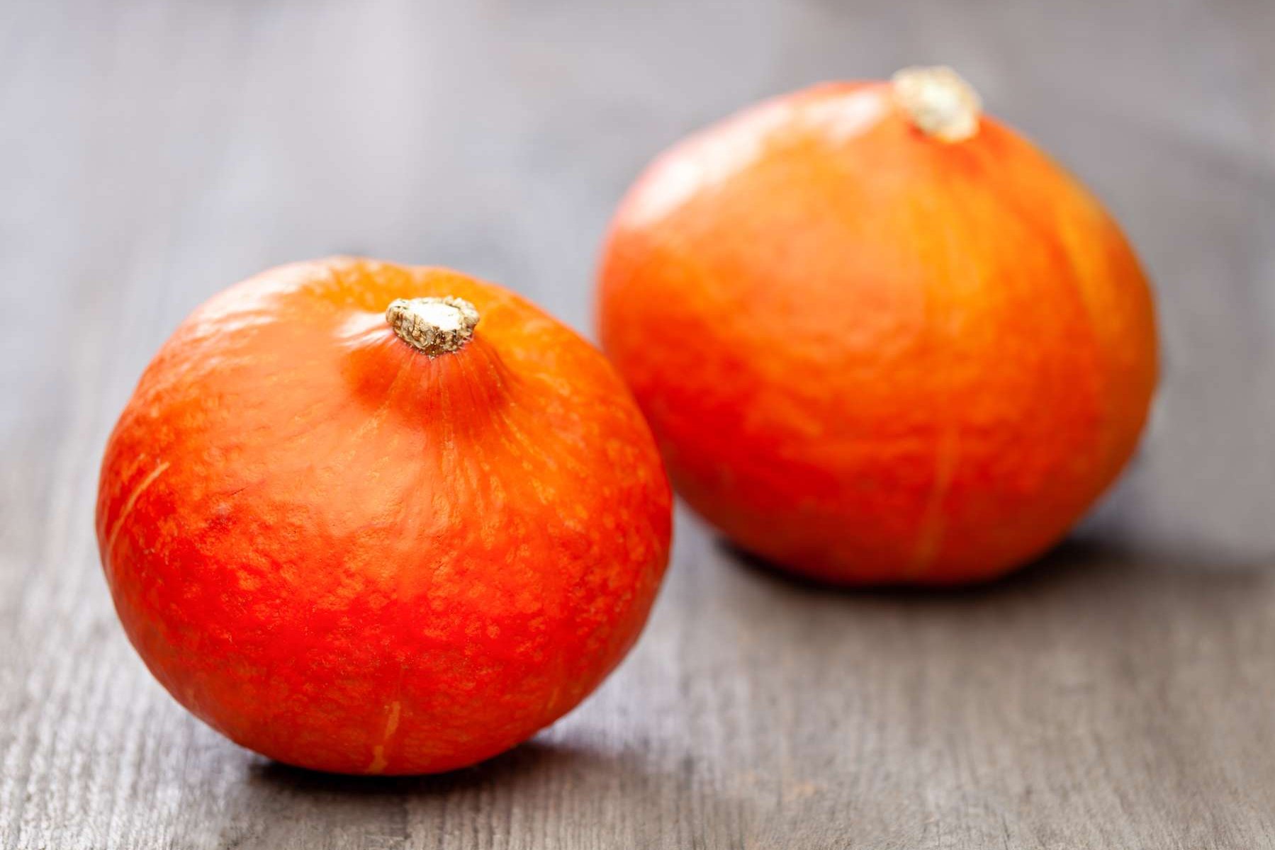 Zwei Speisekürbisse liegen auf einem Holztisch