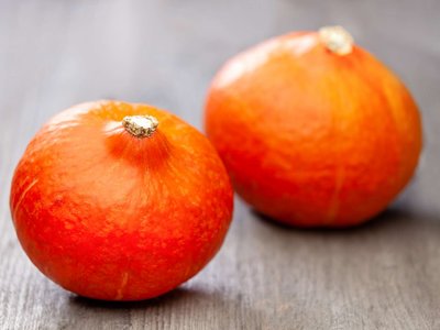 Zwei Speisekürbisse liegen auf einem Holztisch