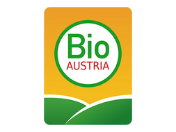 Im stehenden Rechteck ist unten grüne Wiese angedeutet und darüber auf gelbem Himmel ein weißer Kreis mit dem Text Bio Austria