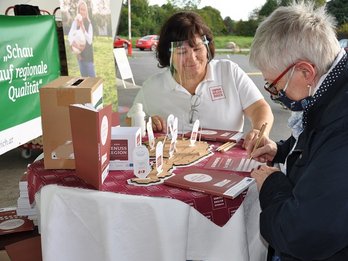 Seminarbäuerin steht mit Konsumentein beim Tisch und füllt mit ihr ein Gewinsspiel aus für Das isst Österreich.
