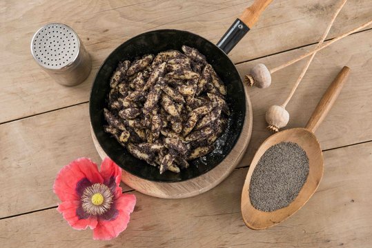 Mohnnudeln in einer Pfanne mit geriebenem Mohn und einer Mohnblüte