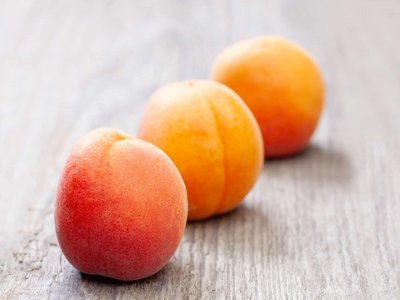 Drei Marillen liegen auf einem Holztisch