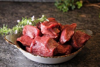 Wildfleisch für Hirschragout roh in einer Schüssel mit Kräutern