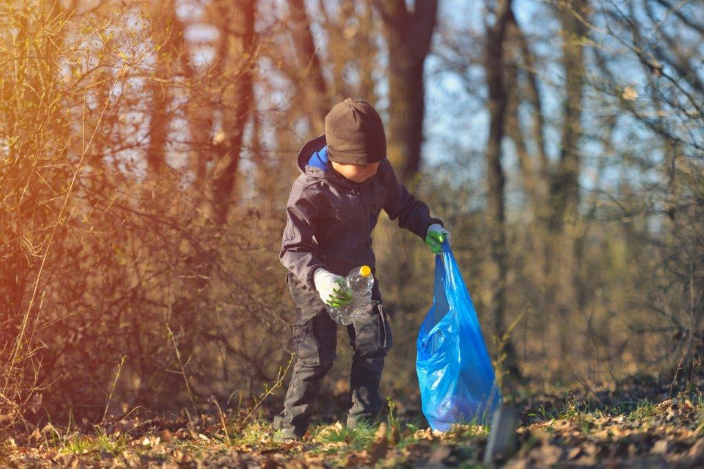 Kind beim Müllsammeln - Achtlos weggeworfener Müll geht auf Kosten der nachfolgenden Generationen.