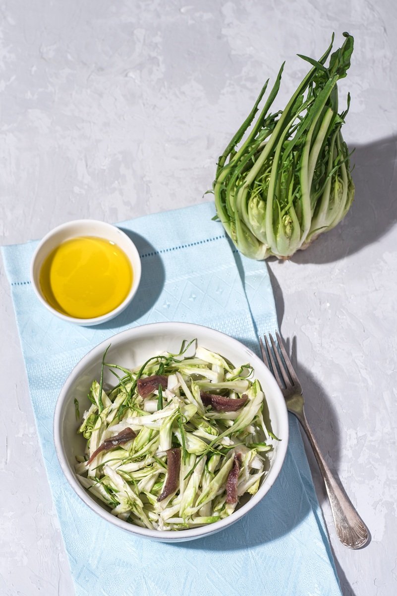 Puntarelle alla romana or asparagus Catalonian chicory salad with anchovy dressing and olive oil, italian food, selective focus, bright sunlight. Italian traditional seasoning recepies