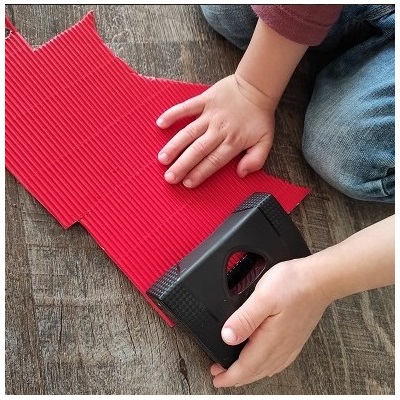 Kind macht Konfetti mit Locher aus Wellkarton