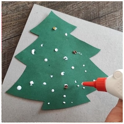 Kind macht Kleber-Punkte auf Christbaum für Konfetti