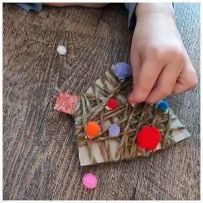 Kind klebt Filzkugeln auf Christbaum